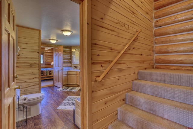 stairs with rustic walls and hardwood / wood-style floors