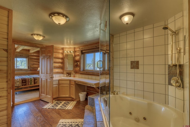 bathroom featuring plenty of natural light, rustic walls, hardwood / wood-style floors, and a textured ceiling