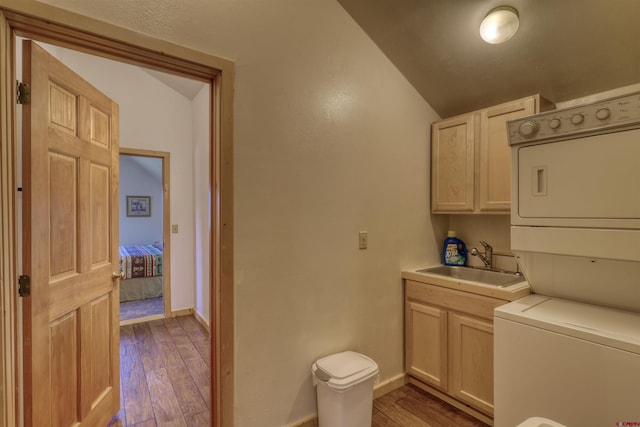 laundry area featuring stacked washer and clothes dryer, light hardwood / wood-style floors, and sink