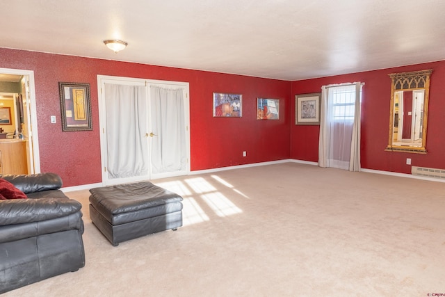 carpeted living room featuring a baseboard heating unit and baseboards