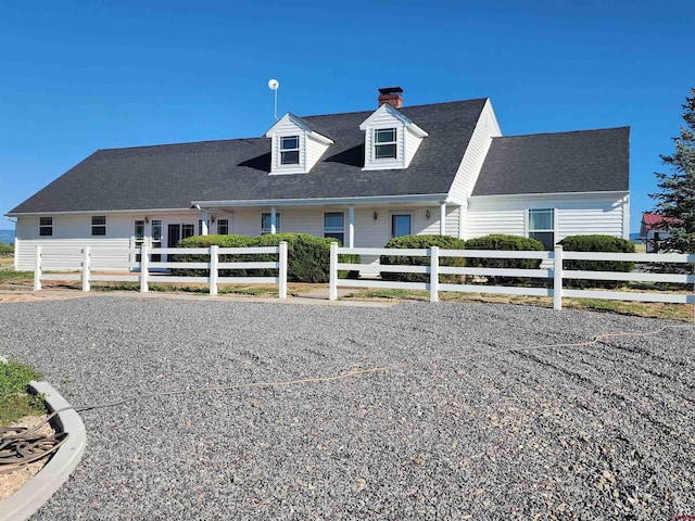 new england style home featuring a shingled roof and fence