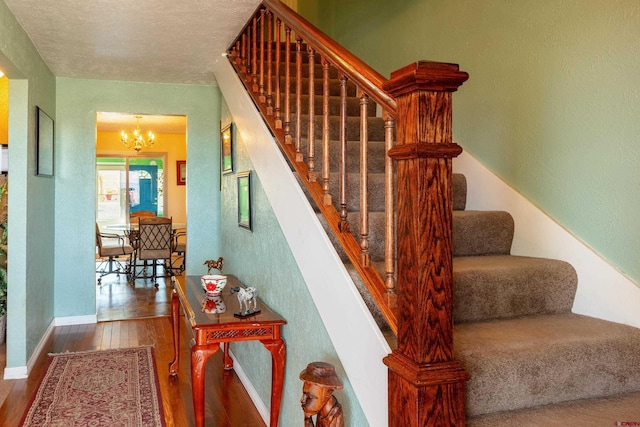 staircase with a chandelier, baseboards, and hardwood / wood-style floors