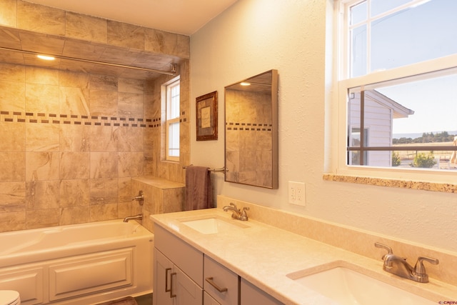 full bathroom featuring plenty of natural light, double vanity, tiled shower / bath combo, and toilet