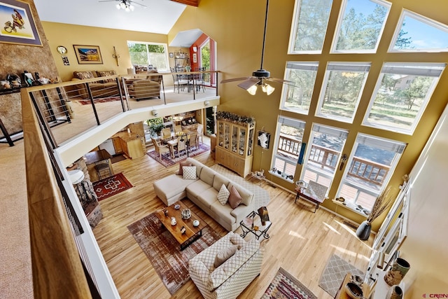 living room featuring wood-type flooring, high vaulted ceiling, and ceiling fan