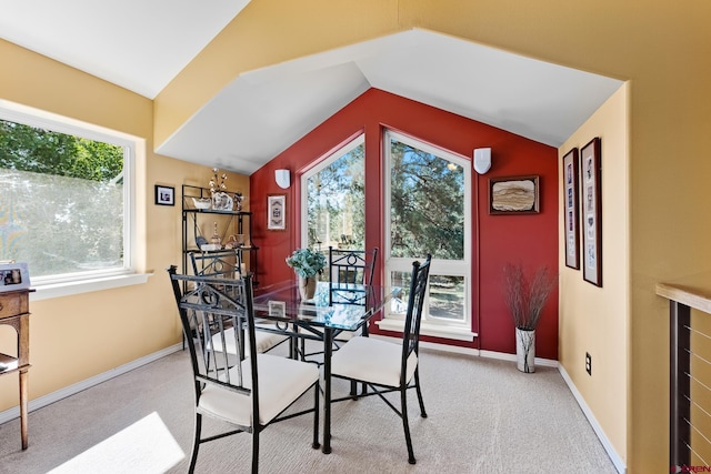 carpeted dining area with vaulted ceiling