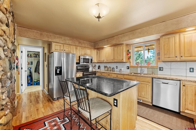 kitchen with stone counters, sink, a kitchen island, a kitchen bar, and stainless steel appliances