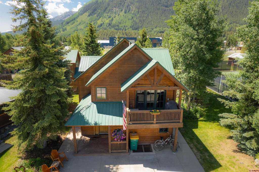 rear view of house with a mountain view and a lawn