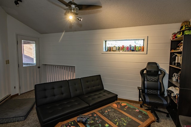 sitting room with ceiling fan, vaulted ceiling, wooden walls, and a textured ceiling