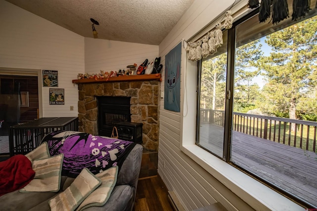 living room featuring lofted ceiling, a stone fireplace, wood walls, a textured ceiling, and hardwood / wood-style floors