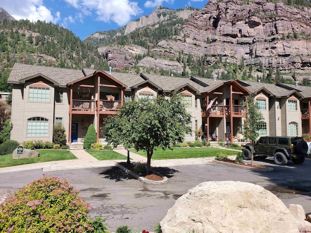 view of front of property featuring a mountain view, a balcony, and a front yard