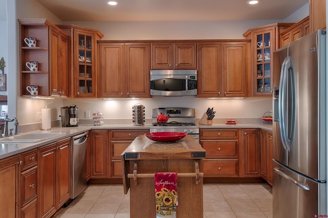 kitchen featuring sink, light tile patterned floors, light stone counters, a kitchen island, and appliances with stainless steel finishes