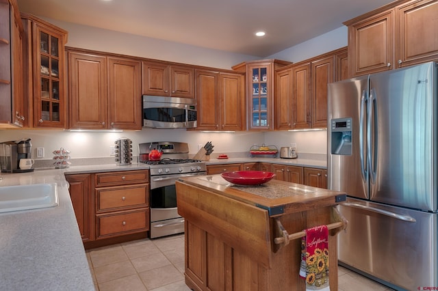 kitchen with a kitchen island, light tile patterned flooring, sink, and appliances with stainless steel finishes