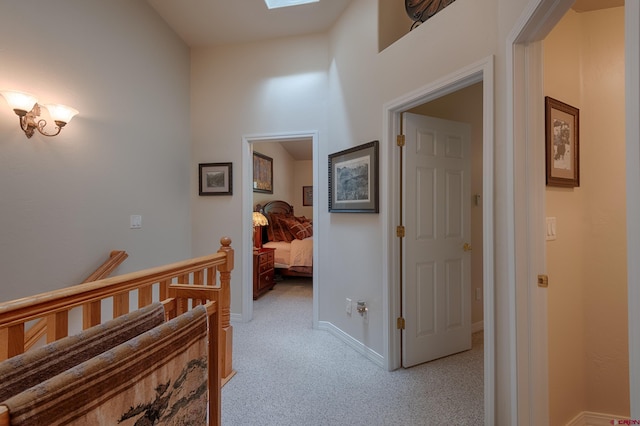 corridor with light colored carpet and a skylight