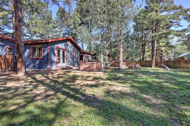 view of yard featuring french doors, a fenced backyard, and a hot tub