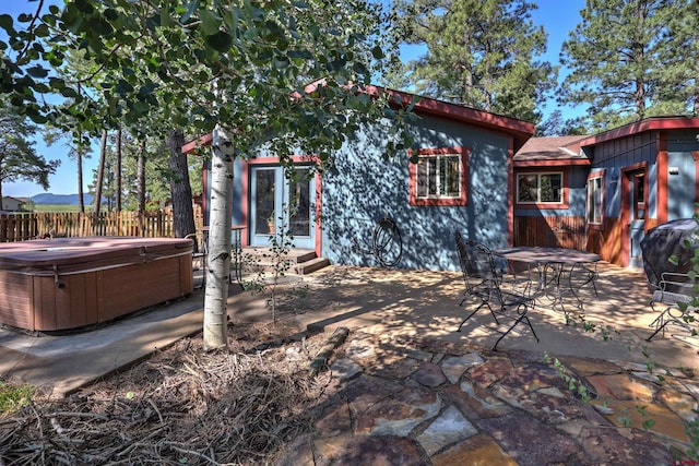 rear view of house with a patio and a hot tub