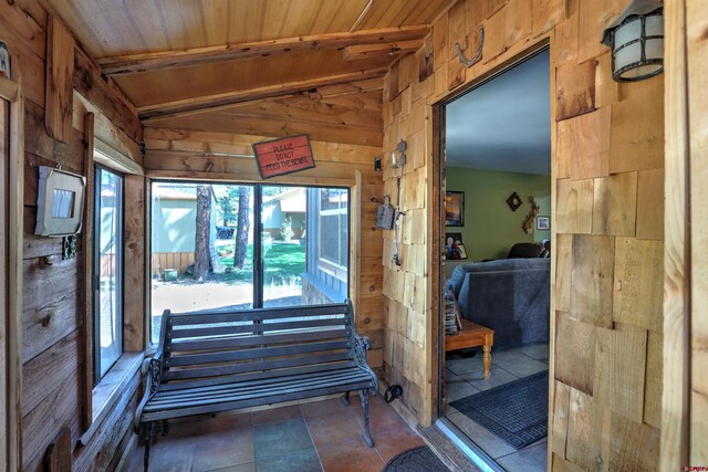 interior space featuring vaulted ceiling with beams, wood ceiling, plenty of natural light, and wood walls