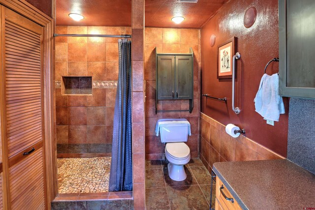 bathroom featuring vanity, toilet, tile patterned floors, and tile walls