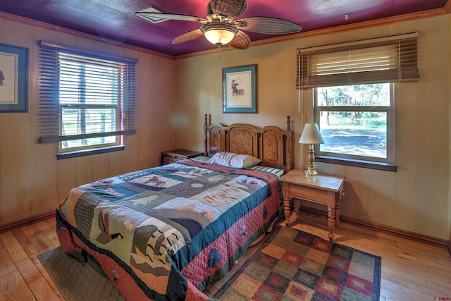 bedroom featuring baseboards, multiple windows, ornamental molding, and wood finished floors