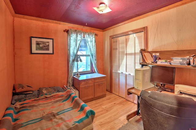 bedroom featuring light hardwood / wood-style floors, crown molding, and a closet