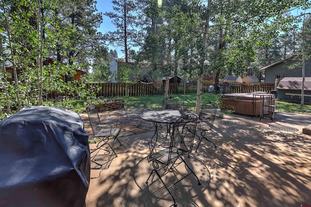 view of patio featuring a hot tub, a fenced backyard, and area for grilling