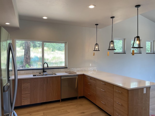 kitchen with stainless steel appliances, a peninsula, a sink, and light countertops