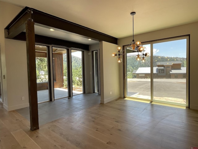 interior space with a healthy amount of sunlight, beam ceiling, baseboards, and wood finished floors
