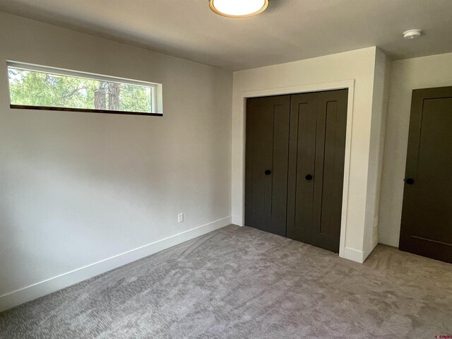unfurnished bedroom featuring a closet, light colored carpet, and baseboards