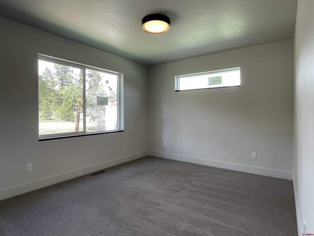 unfurnished room featuring dark carpet, visible vents, and baseboards