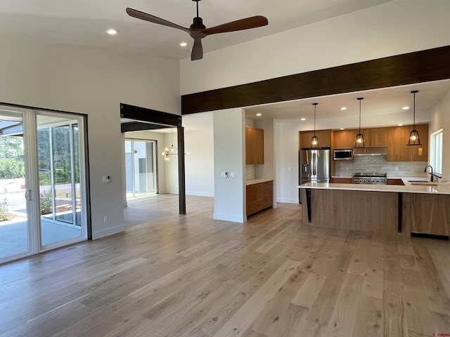 kitchen with decorative light fixtures, light countertops, appliances with stainless steel finishes, a sink, and a peninsula