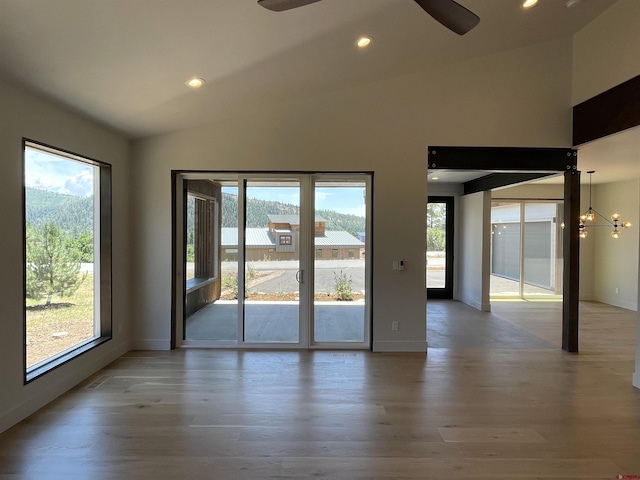 empty room with vaulted ceiling, recessed lighting, wood finished floors, and a healthy amount of sunlight