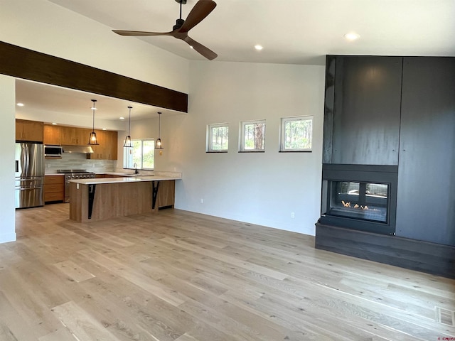 kitchen with appliances with stainless steel finishes, open floor plan, light countertops, and a peninsula