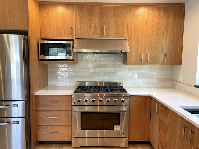 kitchen featuring appliances with stainless steel finishes, light countertops, backsplash, and exhaust hood