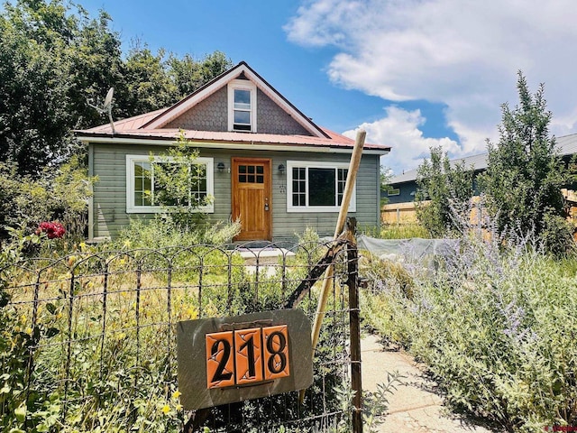 bungalow-style house with metal roof and fence