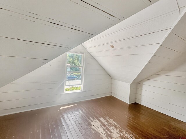 bonus room featuring lofted ceiling, dark hardwood / wood-style flooring, and wooden walls