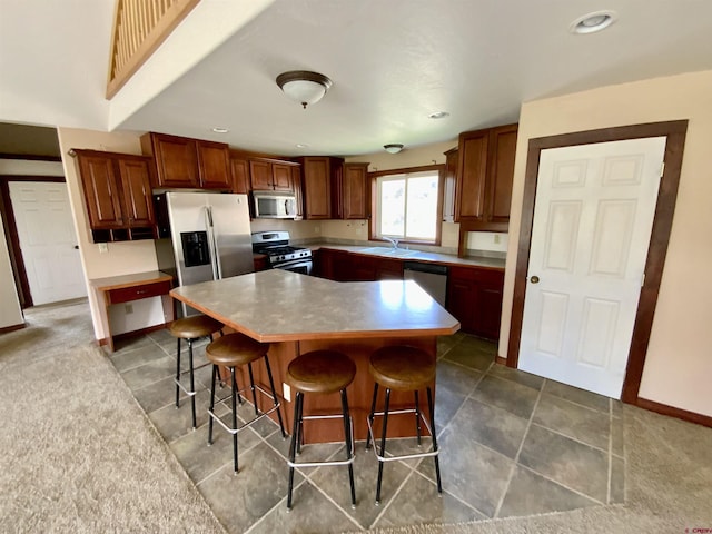 kitchen with a breakfast bar area, a center island, stainless steel appliances, and sink