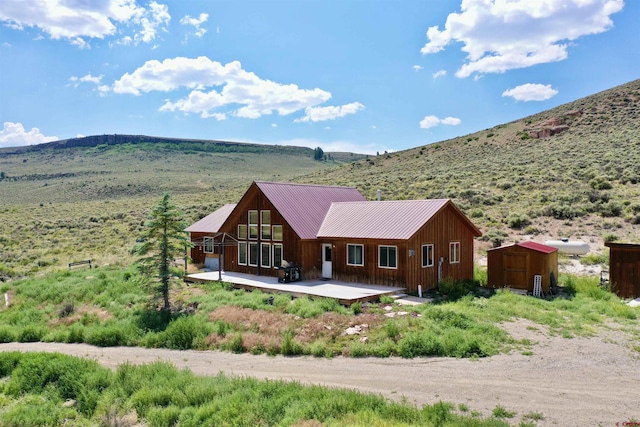 back of property featuring a mountain view and a storage shed