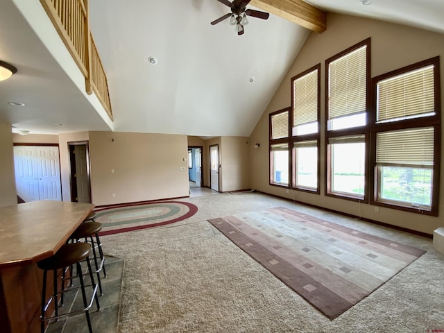 carpeted living room with beam ceiling, ceiling fan, and high vaulted ceiling