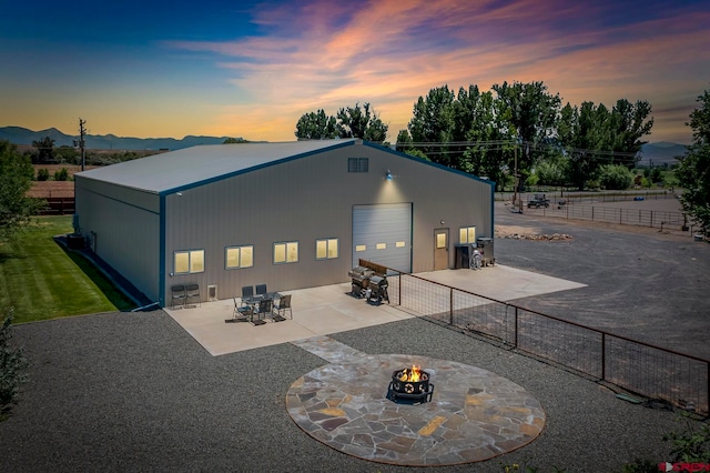 back house at dusk featuring a patio and a fire pit