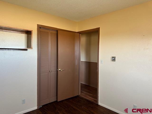 unfurnished bedroom with dark hardwood / wood-style floors and a textured ceiling