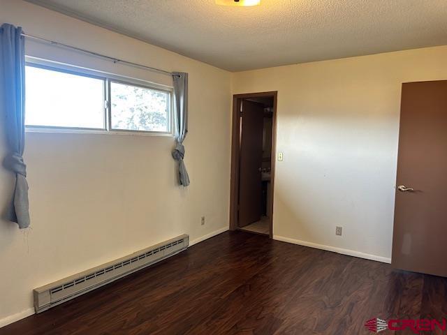 spare room featuring a textured ceiling, dark hardwood / wood-style flooring, and a baseboard radiator