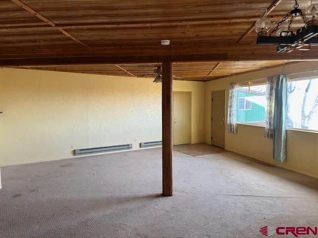 basement featuring baseboard heating, carpet floors, and wood ceiling