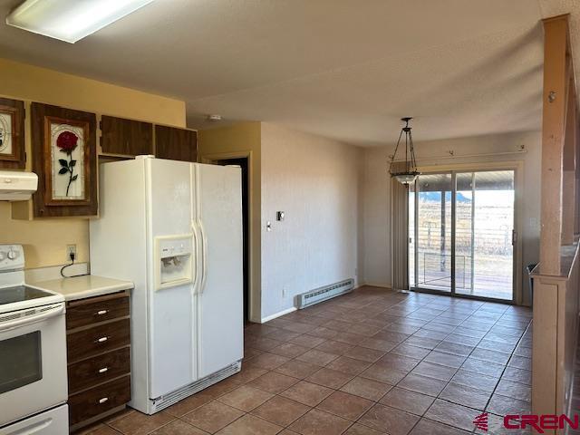 kitchen featuring white appliances, hanging light fixtures, light tile patterned floors, a baseboard radiator, and dark brown cabinets