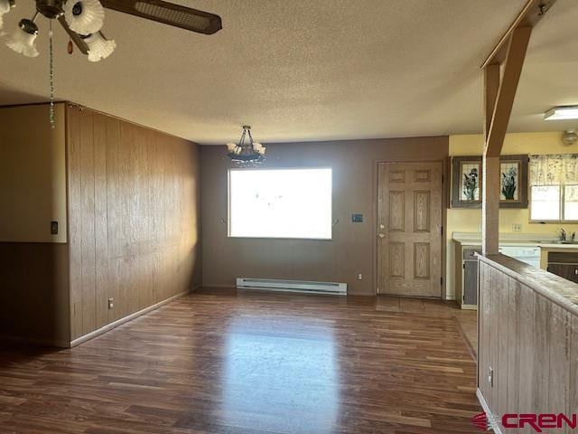 unfurnished dining area featuring dark wood-type flooring, plenty of natural light, baseboard heating, and wooden walls