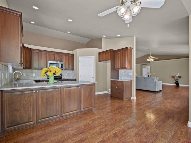 kitchen with vaulted ceiling, appliances with stainless steel finishes, sink, and light stone counters