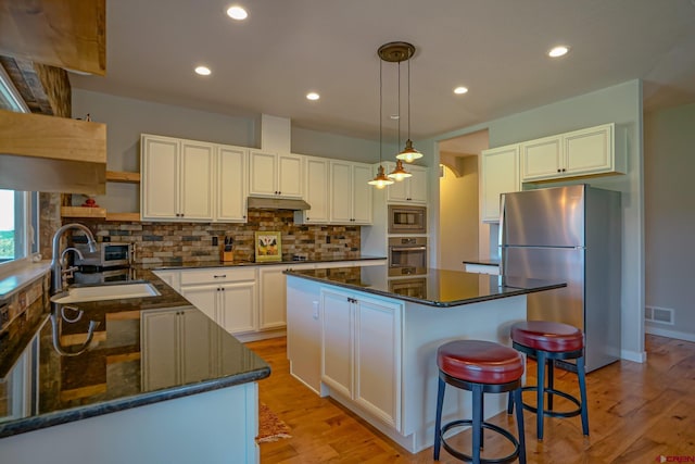 kitchen with sink, white cabinetry, backsplash, hanging light fixtures, and appliances with stainless steel finishes