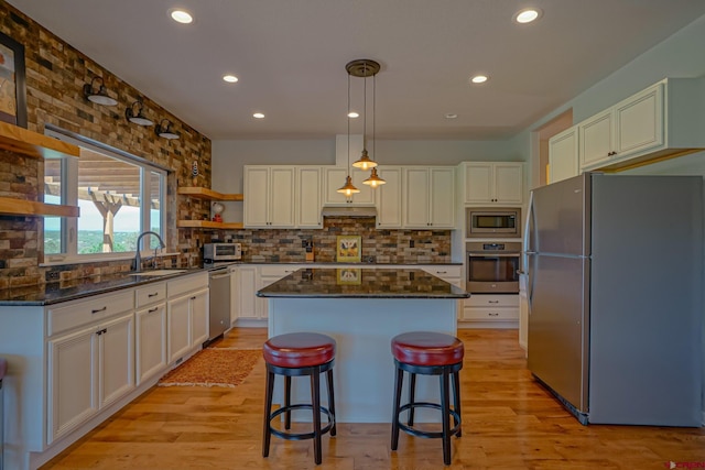 kitchen featuring hanging light fixtures, a center island, stainless steel appliances, white cabinetry, and a kitchen breakfast bar