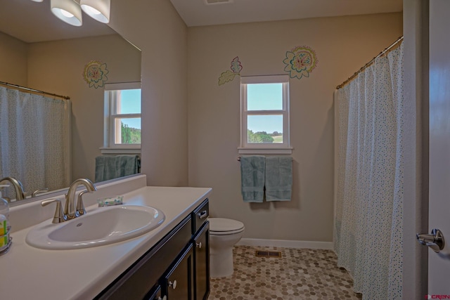 bathroom with toilet, vanity, tile patterned floors, and a wealth of natural light