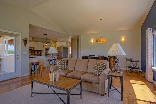 living room with light hardwood / wood-style floors and vaulted ceiling