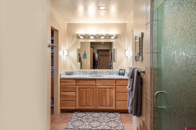 bathroom with a shower with door, vanity, and tile patterned flooring