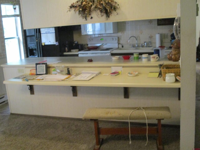 kitchen with white range with electric stovetop, a kitchen breakfast bar, sink, and kitchen peninsula